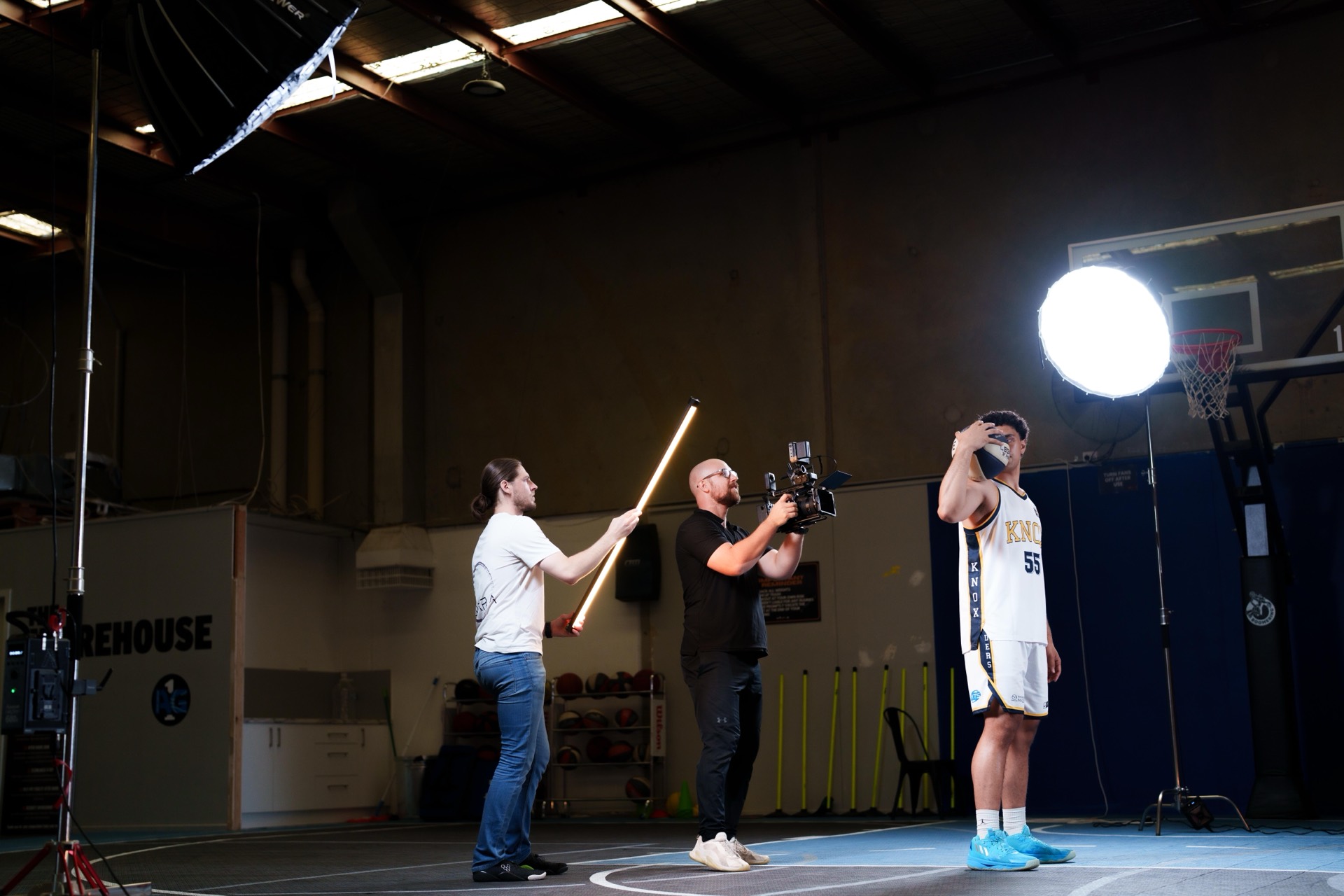Sports film crew lighting a basketball media day on court